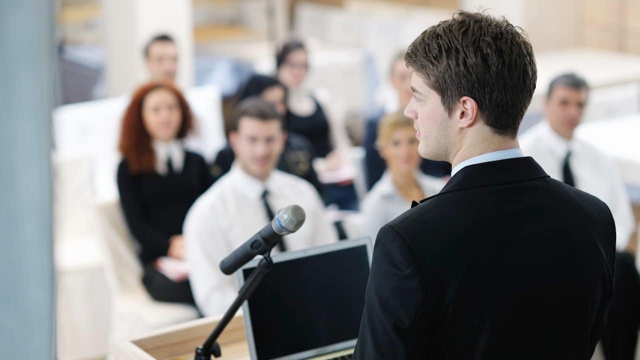 immagine con persona che parla durante una presentazione