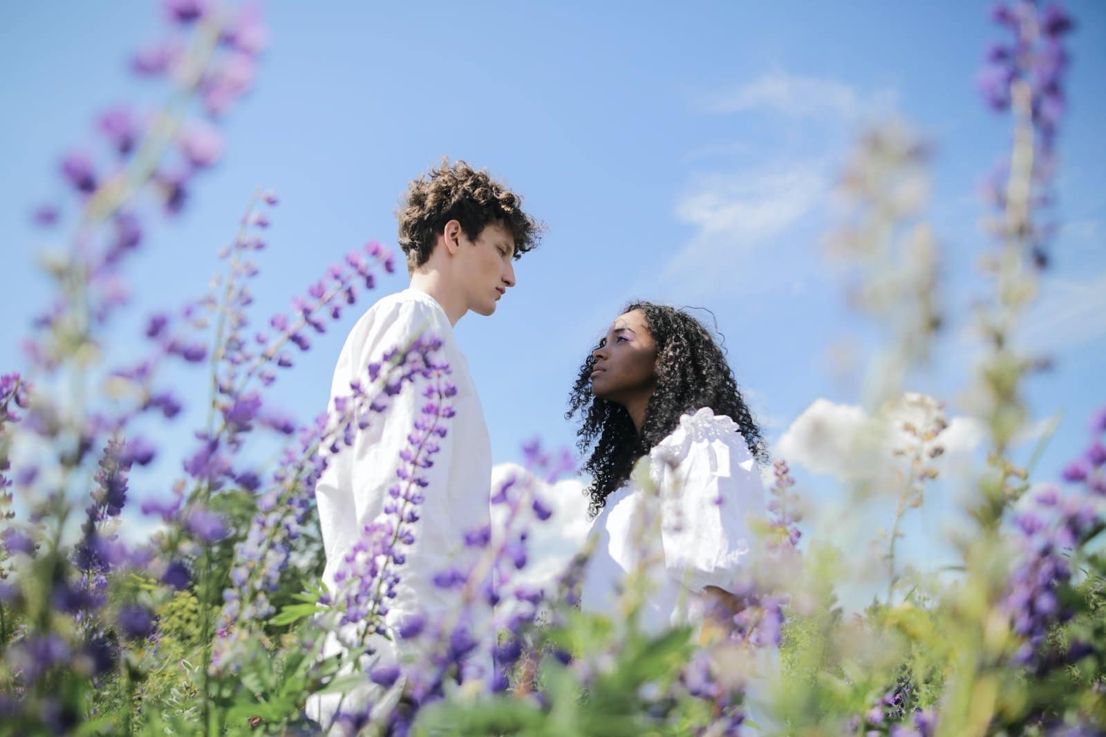 man and woman kissing on purple flower field