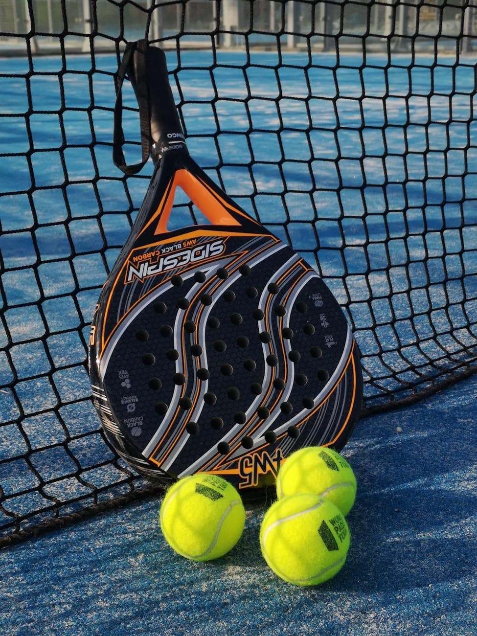 padel racket and bright balls on tennis court